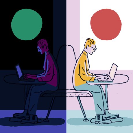 A man sitting and working on his computer in both the dark and the light